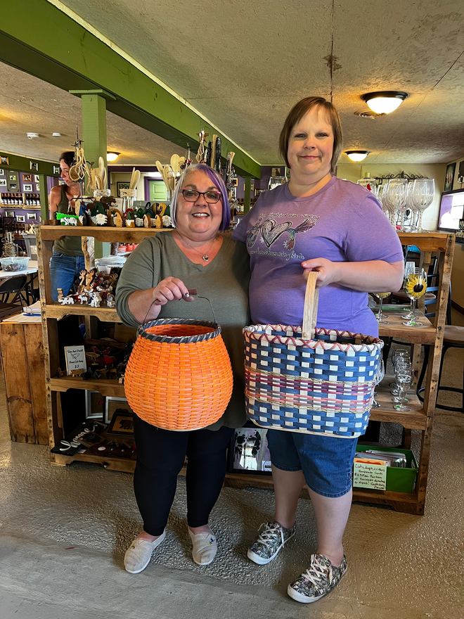 Two guests in the tasting room holding the baskets they wove at a workshop