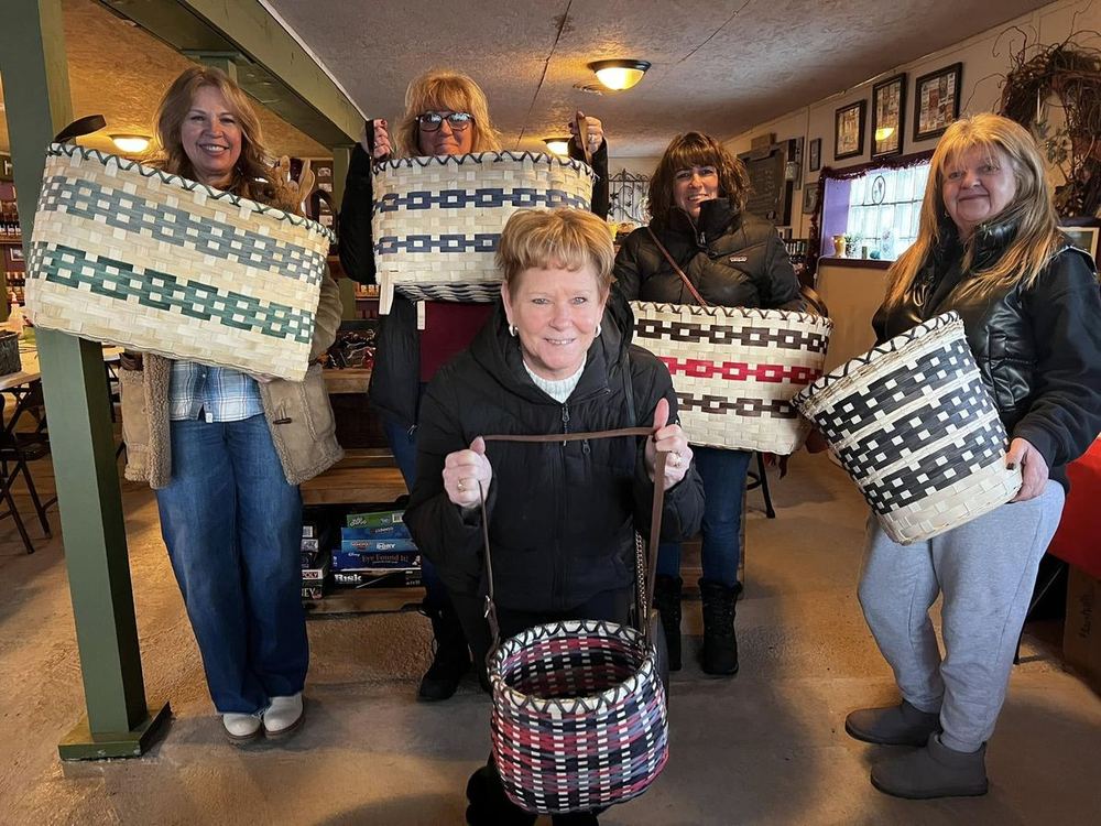 Guests holding baskets they wove at a winery workshop
