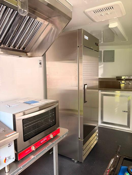 Inside the food trailer &mdash; commercial oven, fridge and prep space
