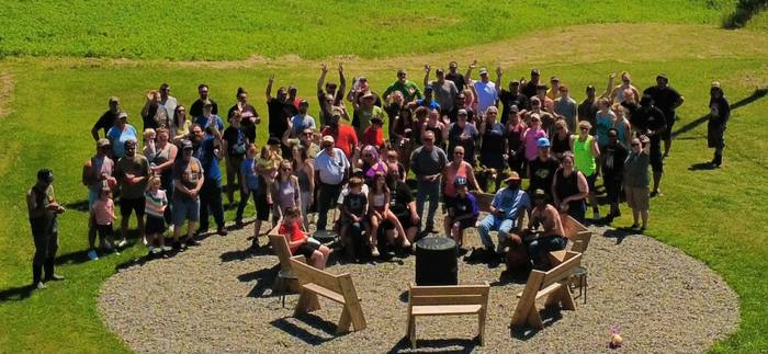 A crowd gathered around the fire pit on a summer afternoon