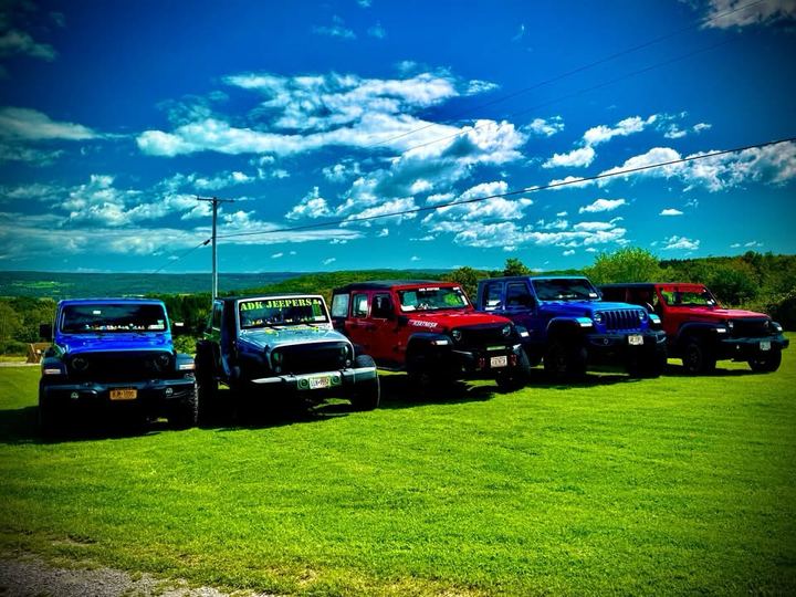 A line of Jeeps parked on the grass above the valley on Jeep Day