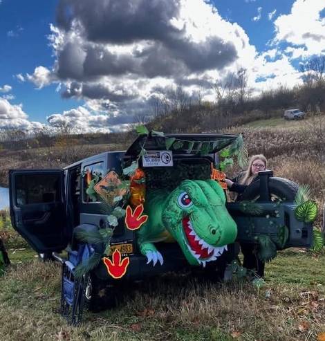 A Jeep decorated with a giant dinosaur for trunk-or-treat